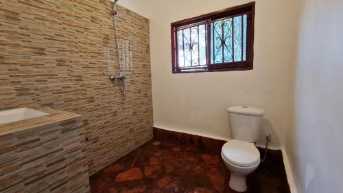 a bathroom with a toilet and a shower and a window at GKAT Resort in Mbarara