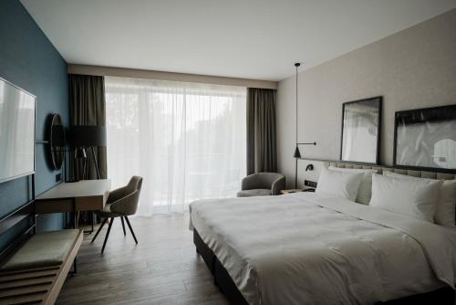 a hotel room with a large bed and a desk at Radisson Resort Kołobrzeg in Kołobrzeg