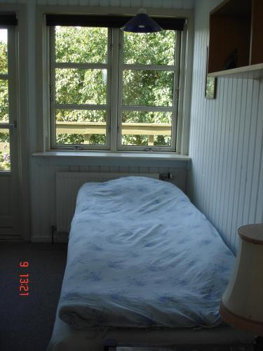 a bed sitting in a room with two windows at Munkebo B&B, Thy in Thisted