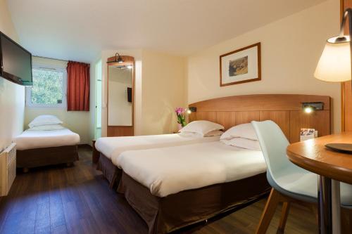 a hotel room with two beds and a desk at Comfort Hotel Amiens Nord in Amiens