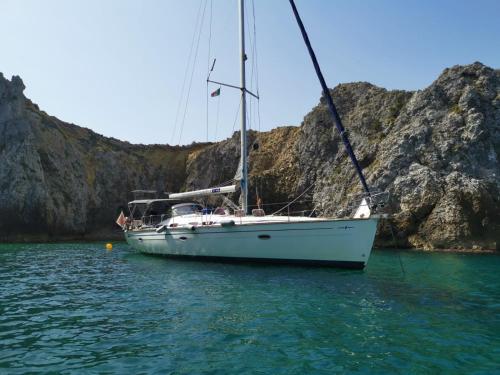 a sailboat sitting in the water next to a mountain at B&B La Maison del Borgo in Rodi Garganico