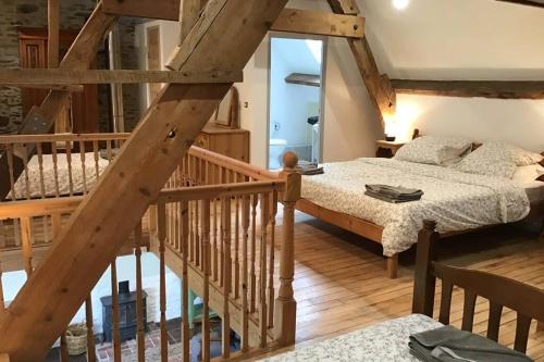 a bedroom with a bed and a wooden staircase at La Porcherie at La Grande Houssaye in Villiers-Fossard