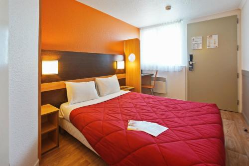 a bedroom with a red bed with a red blanket at Première Classe Villejust in Villejust
