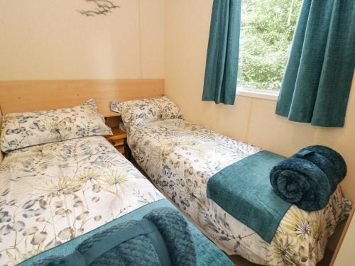 two beds in a small room with a window at Vista in Moelfre