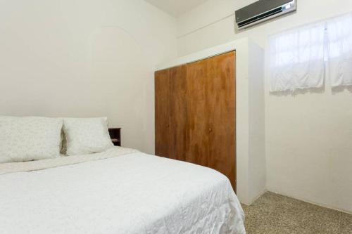 a bedroom with a white bed and a wooden door at Comfortable and Affordable Deal Close to Beach and Rainforest in Rio Grande