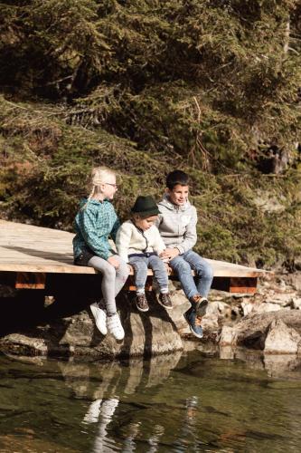 three people sitting on a dock by the water at Almfamilyhotel Scherer in Obertilliach