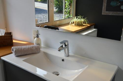 ein weißes Waschbecken in einem Badezimmer mit einem Spiegel in der Unterkunft Cottage Marie-Henriette in Spa