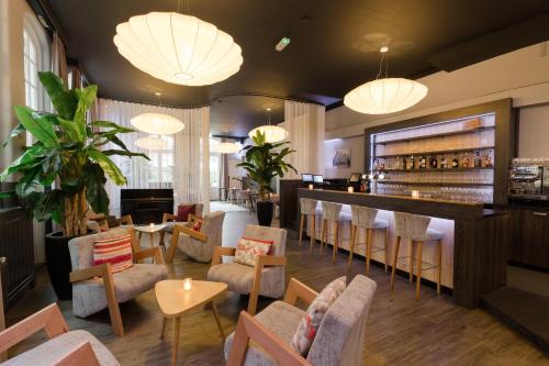 a restaurant with a bar and chairs and lights at Boutique Hotel 't Lansink in Hengelo