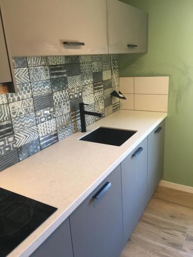 a kitchen with white cabinets and a tile wall at Appartement Buiten de Veste 28 in Veere