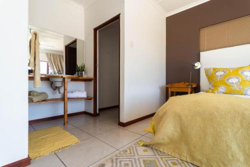 a bedroom with a bed with a yellow bedspread and a mirror at Melkboomsdrift Guest House & Conference Centre in Vredendal
