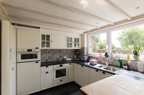 a kitchen with white cabinets and a large window at Luppolo vakantiehuis Westhoek in Alveringem