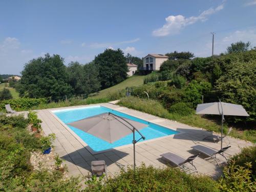 una piscina con sillas, una sombrilla y una casa en Gites Arnoult en Damiatte