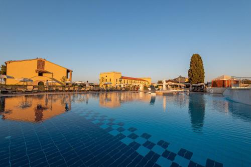 ein großer Wasserpool mit Gebäuden im Hintergrund in der Unterkunft Salvapiano Holiday Ranch in Riotorto