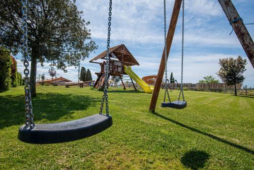 two swings in a park with a playground at Salvapiano Holiday Ranch in Riotorto