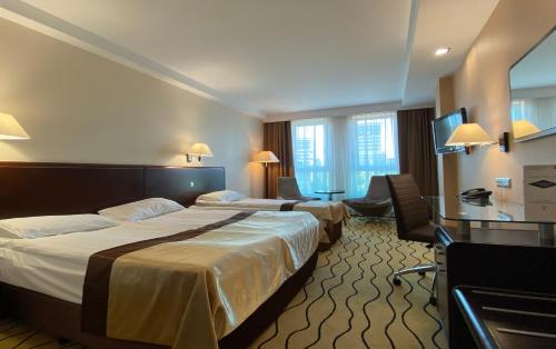 a hotel room with two beds and a desk at Ambasador Centrum in Łódź