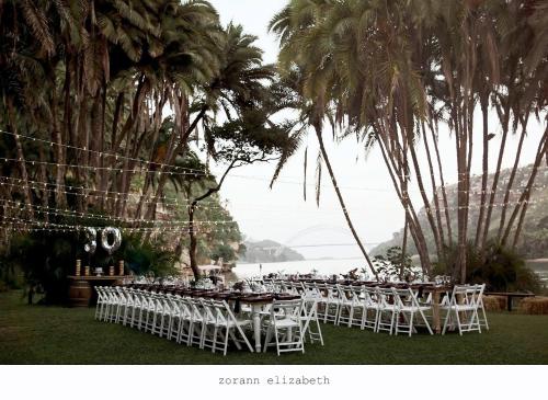 a group of tables with white chairs and palm trees at Umtamvuna River Lodge in Port Edward
