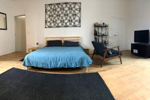 1 dormitorio con 1 cama, 1 silla y TV en Studio et terrasse au sein d'un manoir XVIIème en Montauban-de-Bretagne