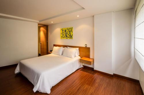 a bedroom with a large white bed and wooden floors at Travelers Obelisco Apartamentos in Bogotá