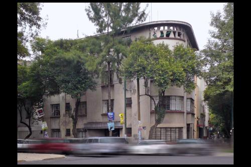 Un edificio con coches pasando a toda velocidad frente a él. en Casa Nuevo Leon, en Ciudad de México