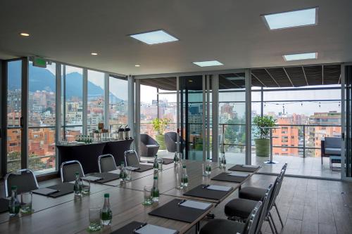 a conference room with tables and chairs and windows at GHL Bioxury Hotel in Bogotá