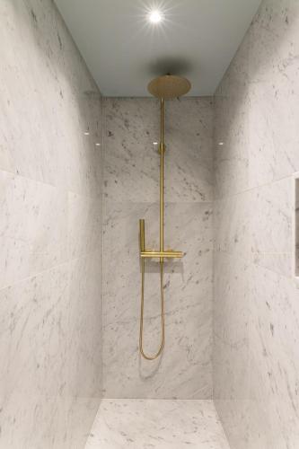 a bathroom with a shower with white marble walls at Molenmeers Boutique Guesthouses in Bruges