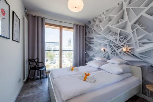 a bedroom with a white bed and a large window at ApartHotel Kolejowa Apartamenty in Warsaw