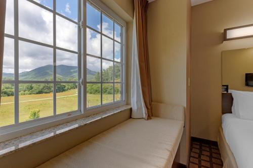 a bedroom with a large window with a mountain view at Microtel Inn & Suites Dillsboro/Sylva in Dillsboro