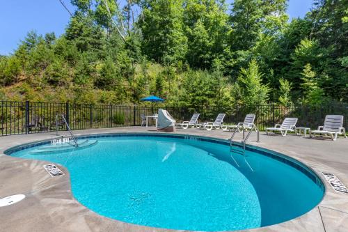 a swimming pool with chairs and a table and an umbrella at Microtel Inn & Suites Dillsboro/Sylva in Dillsboro