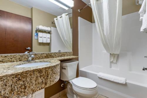 a bathroom with a toilet and a sink and a tub at Microtel Inn & Suites Dillsboro/Sylva in Dillsboro