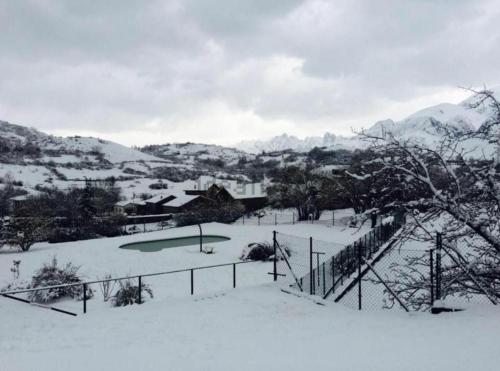 a yard covered in snow with mountains in the background at Refugio del Cares in Ortiguero