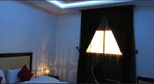 1 dormitorio con cama y ventana con cortina en شقق قمة الرفاء للوحدات السكنيه, en Riad