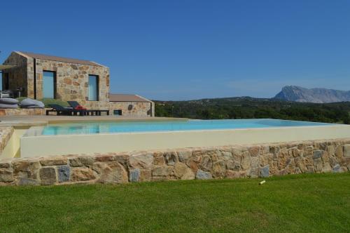 una piscina con un muro di pietra accanto a una casa di La Janna di Lianti a Puntaldia