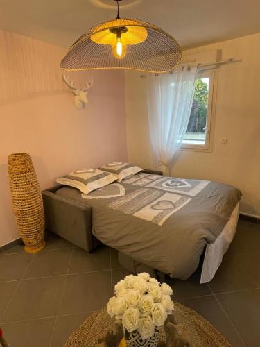 Dormitorio con cama con arreglo floral en el suelo en Studio calme et cosy, en Saint-Julien-les-Villas