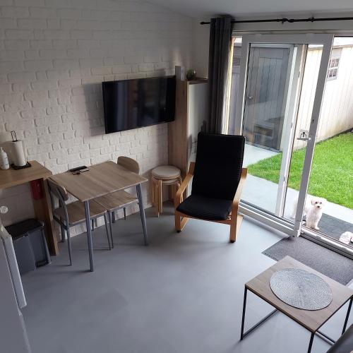 sala de estar con mesa, sillas y TV en Apartament Beti, en Oostkamp
