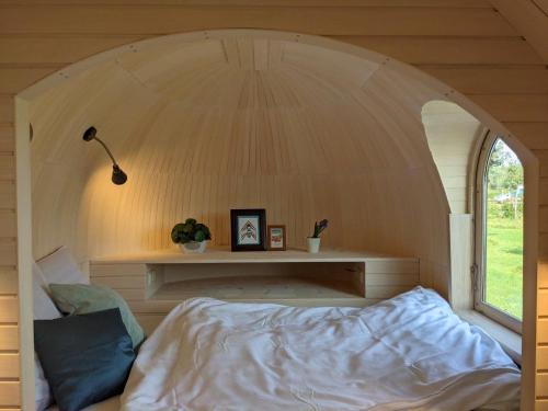 Ce lit se trouve dans un dortoir doté d'une fenêtre cintrée. dans l'établissement Camping Houtum, à Kasterlee