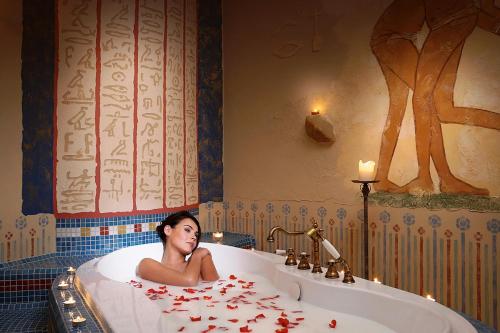 Una donna sdraiata in una vasca da bagno con petali di rosa di Papuga Park Hotel Wellness&Spa a Bielsko-Biała