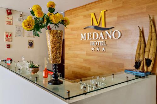 a melona hotel sign and flowers on a glass counter at Hotel Médano in Trujillo