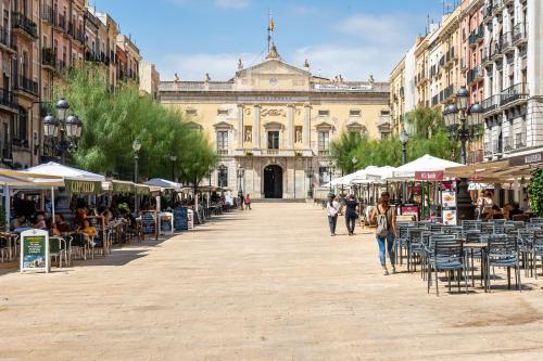 a street with tables and chairs in front of a building at Hauzify I Domus Tarragona in Tarragona