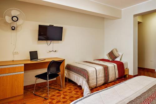 a bedroom with a bed and a desk with a computer at Hotel Médano in Trujillo