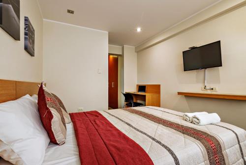 a hotel room with a bed with a television on the wall at Hotel Médano in Trujillo