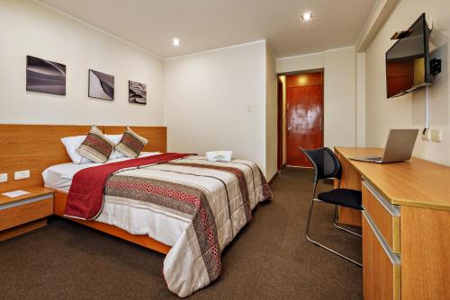 a hotel room with a bed and a desk with a laptop at Hotel Médano in Trujillo