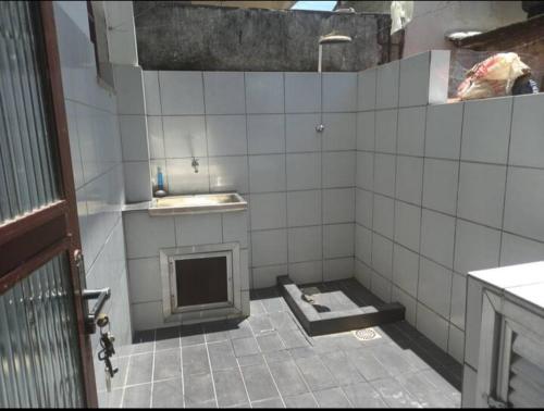 une salle de bain carrelée avec une cheminée et un lavabo dans l'établissement Casa de Praia Ibicuí, à Mangaratiba