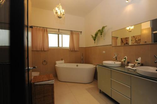 a bathroom with a tub and two sinks and a bath tub at Instyle Residences at Infiniti Blu in Sosúa