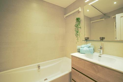 ein Badezimmer mit einem Waschbecken, einer Badewanne und einem Spiegel in der Unterkunft Charmant studio à Méribel avec cheminée in Méribel