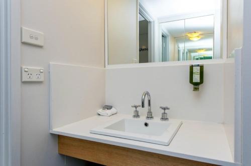 a bathroom with a sink and a mirror at Alpha Hotel Canberra in Canberra