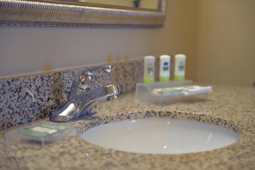 een wastafel in de badkamer met een kraan en een spiegel bij Country Inn & Suites by Radisson, Washington at Meadowlands, PA in Washington