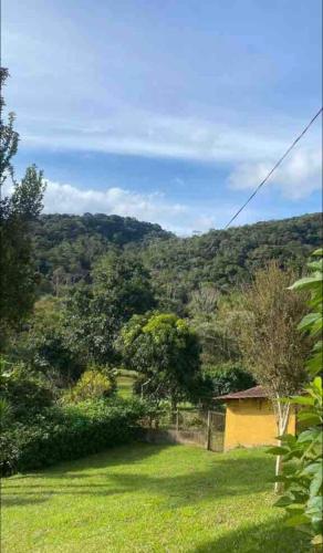 a yellow house in a field of grass with trees at Chácara espaçosa e aconchegante em Juquitiba Sp in Juquitiba