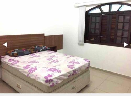 a bedroom with a bed with a flowery comforter and a window at Chácara espaçosa e aconchegante em Juquitiba Sp in Juquitiba