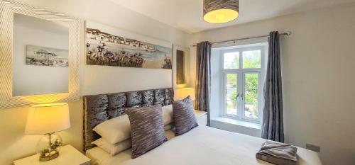 a bedroom with a bed with a large window at Driftwood Cottage, Luxury character cottage in The English Riviera, close to the picturesque precinct of St Marychurch, a short walk to the stunning beaches of Babbacombe and Oddicombe! in Torquay