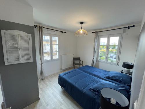 une chambre avec un lit bleu et deux fenêtres dans l'établissement superbe villa au pied de Disneyland et val d'Europe, à Serris